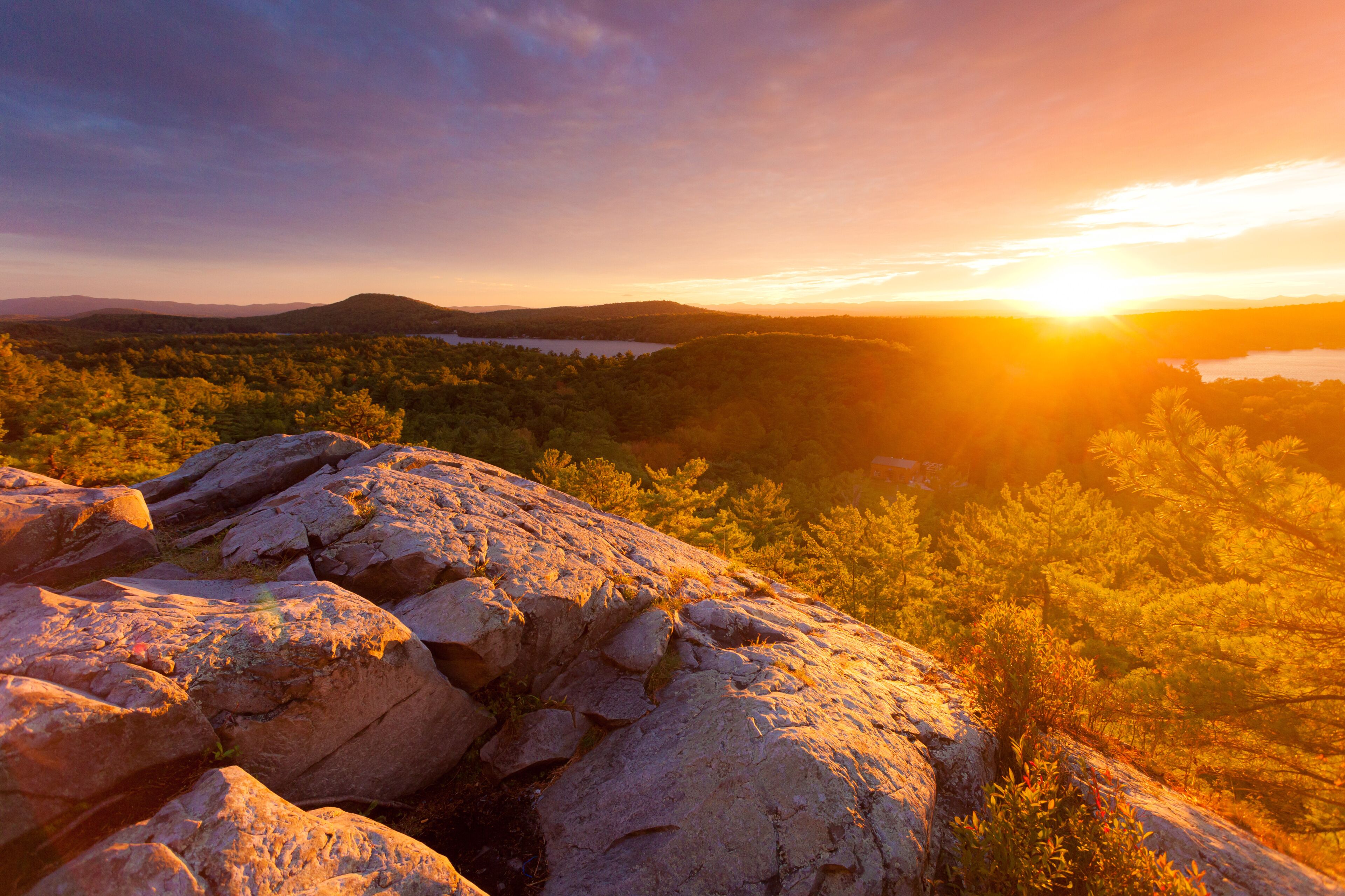 Rocky mountaintop overlooking Lake Dunmore and forest at sunset during autumn