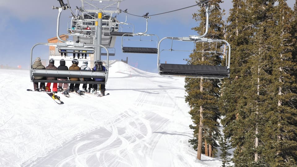 A ski lift with skiers descending a snowy slope.