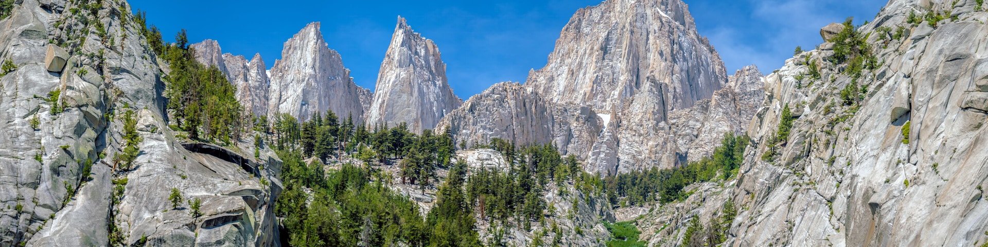 A rugged mountain landscape with prominent rocky peaks and dense forest.