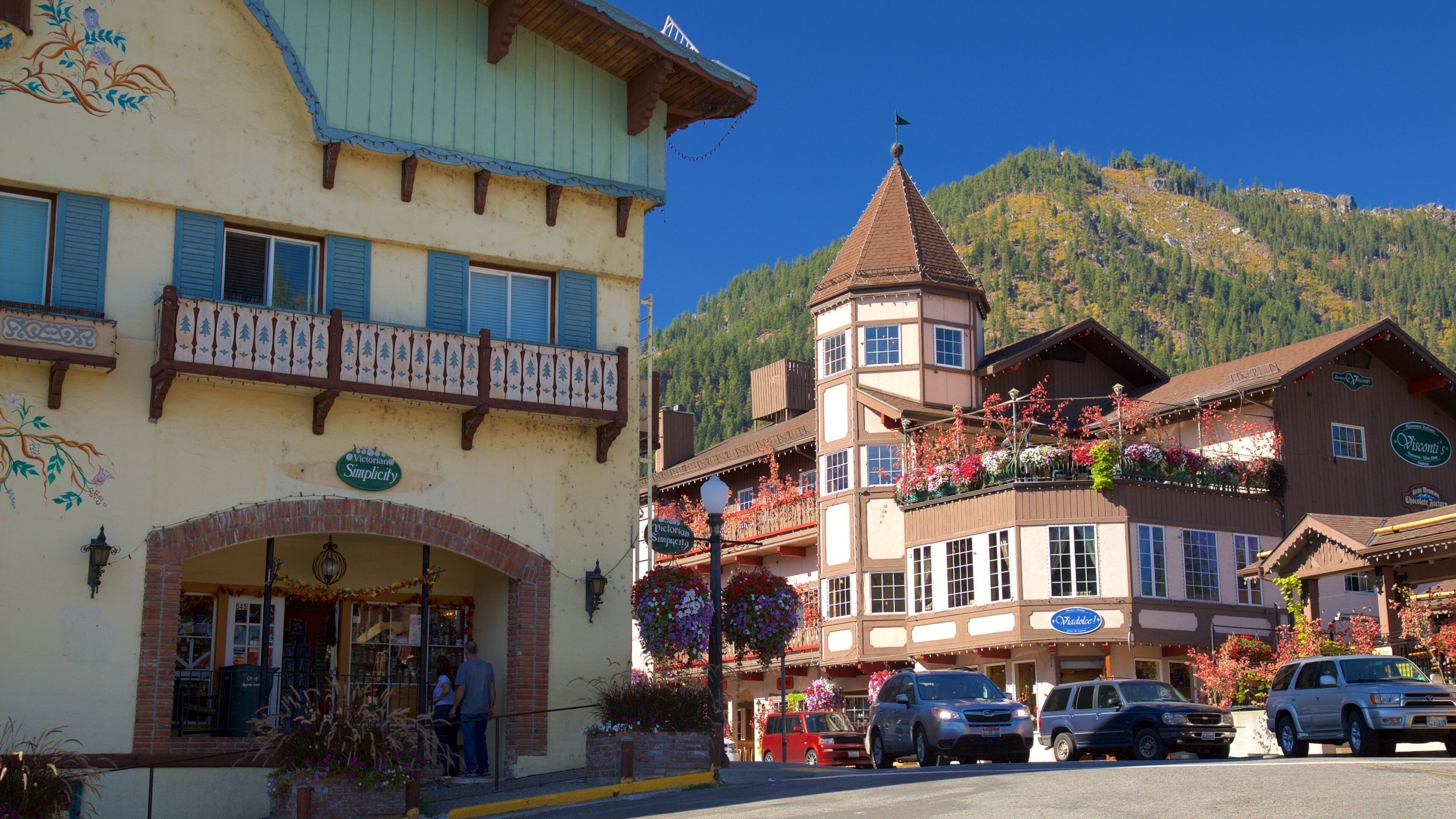 A traditional European town with colorful buildings, a church, and a mountain backdrop.
