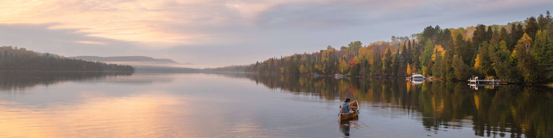 People are boating on Caribou Lake on a fogy morning