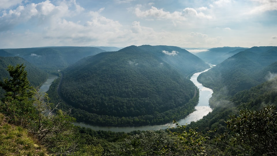 A river winding through a forested valley with rolling hills in the background.