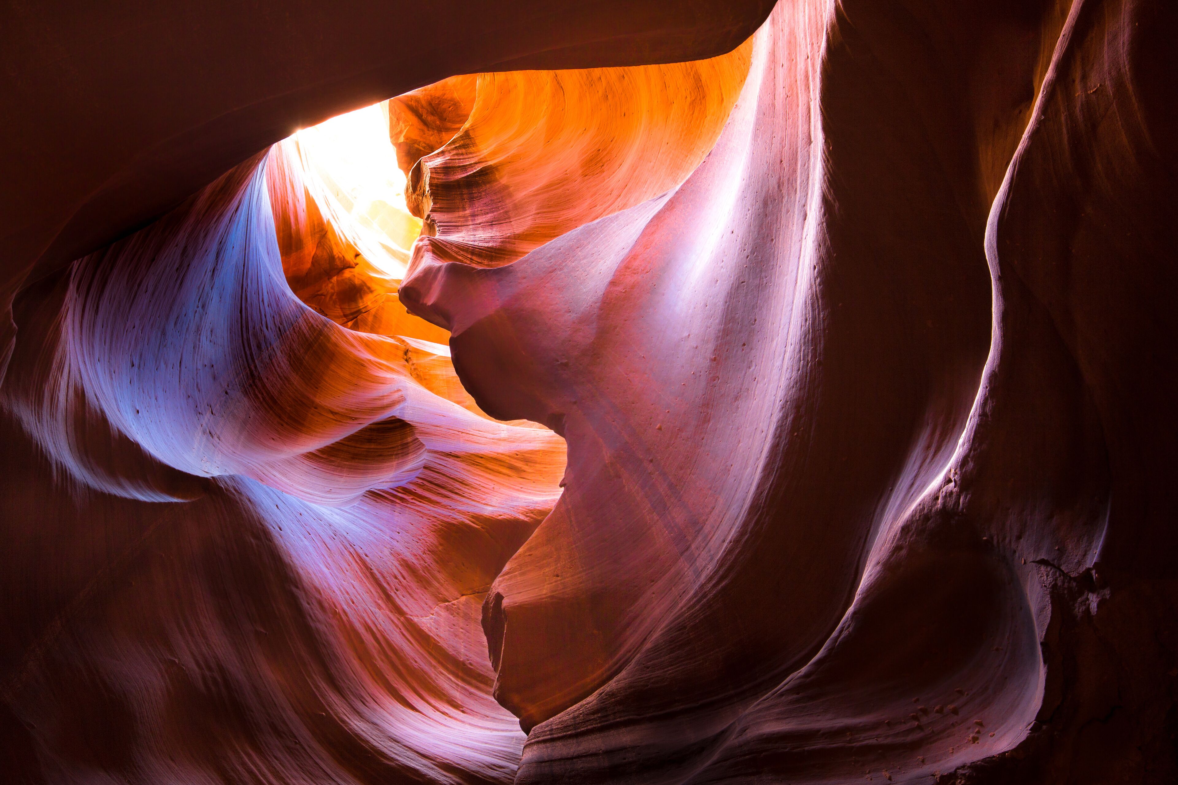 A narrow canyon with smooth, curved rock walls and a narrow opening.