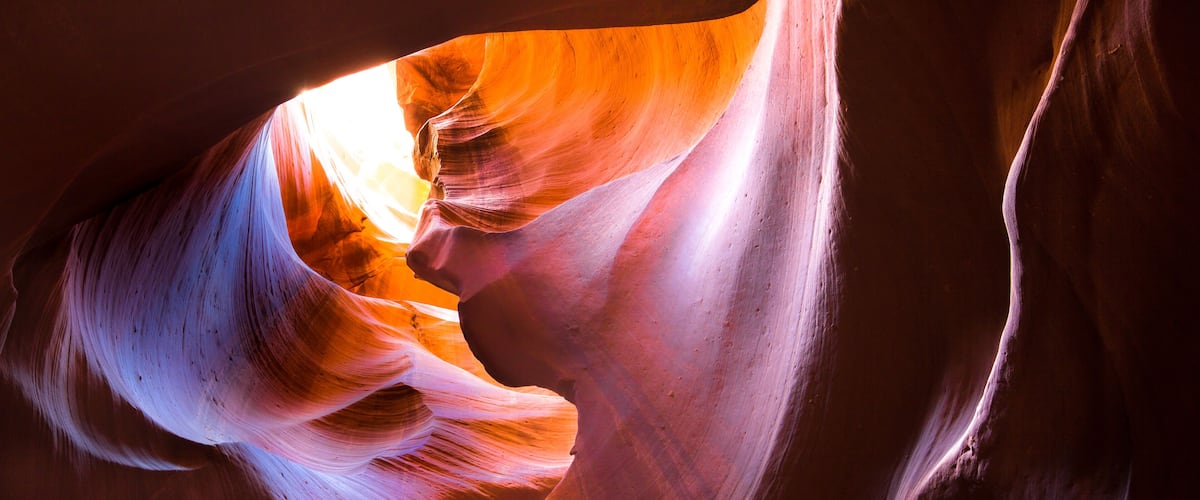 A narrow canyon with smooth, curved rock walls and a narrow opening.