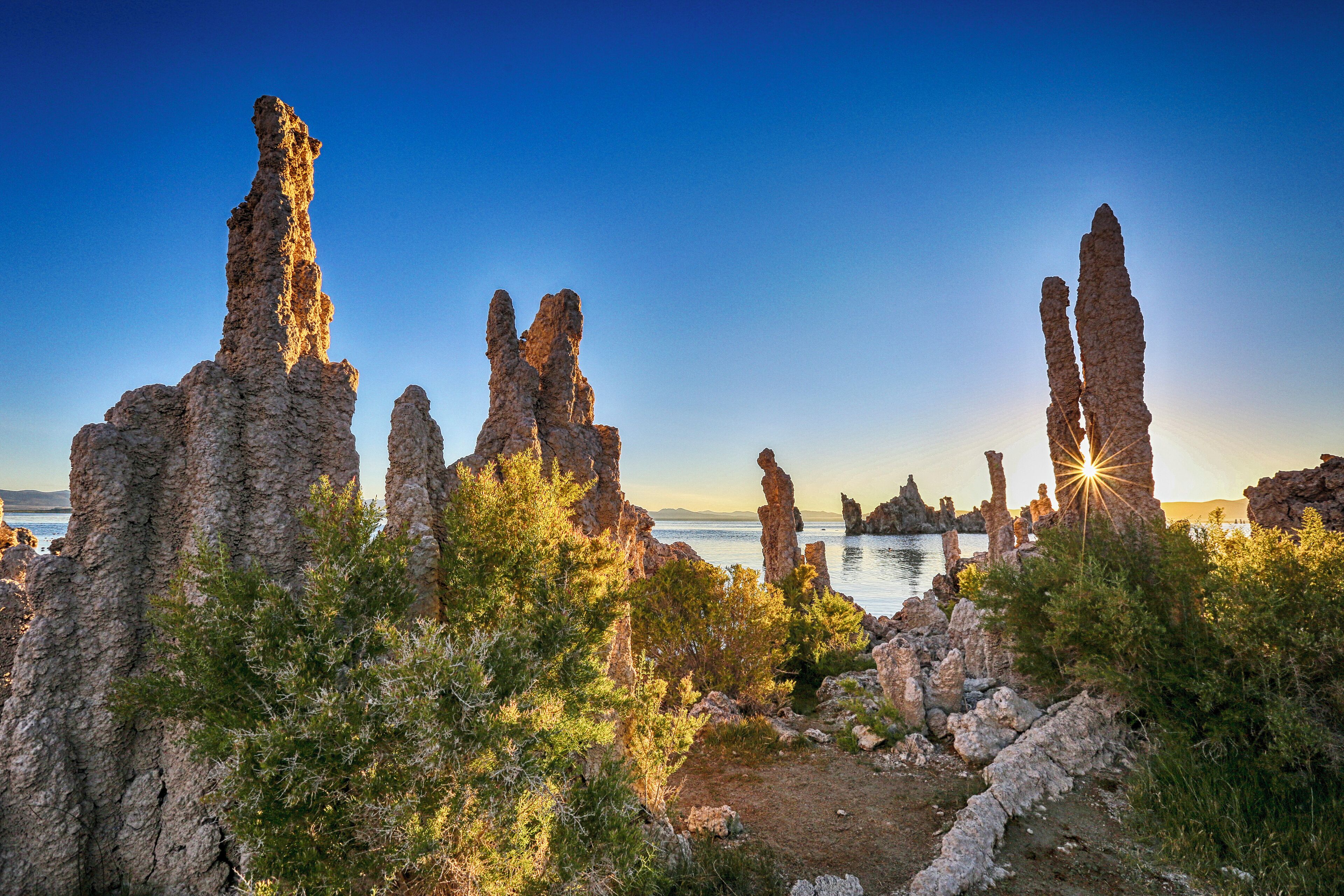 A coastal landscape with tall, rugged rock formations and a clear blue sky.