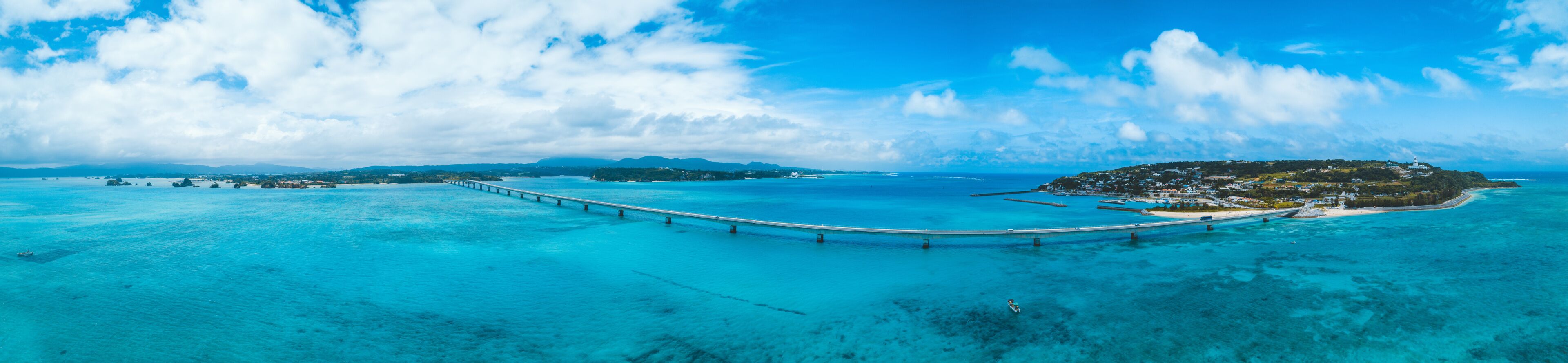 Un paisaje costero con un puente largo, aguas turquesas cristalinas y una pequeña isla con edificios.