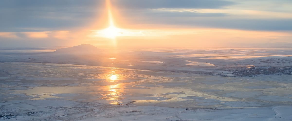 Panoramic aerial view of sunset. Arctic landscape. The northern city of Anadyr is located on the banks of the Anadyr estuary, surrounded by snow-covered tundra. Cold autumn in Chukotka Region. Russia.