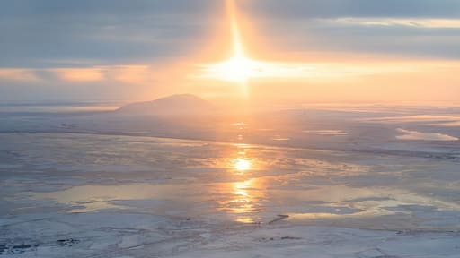 Panoramic aerial view of sunset. Arctic landscape. The northern city of Anadyr is located on the banks of the Anadyr estuary, surrounded by snow-covered tundra. Cold autumn in Chukotka Region. Russia.