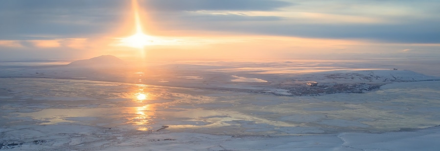 Panoramic aerial view of sunset. Arctic landscape. The northern city of Anadyr is located on the banks of the Anadyr estuary, surrounded by snow-covered tundra. Cold autumn in Chukotka Region. Russia.