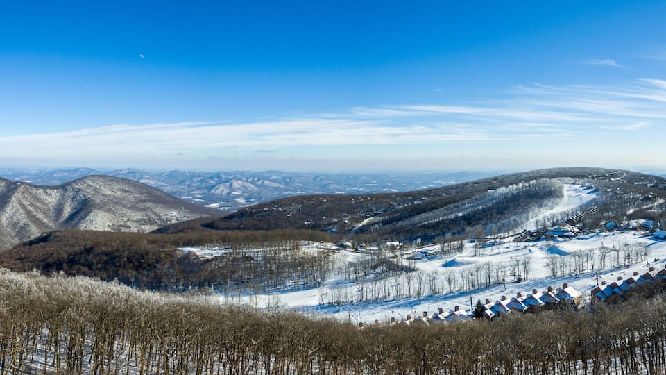A snow-covered mountain landscape with a ski resort and a clear blue sky.