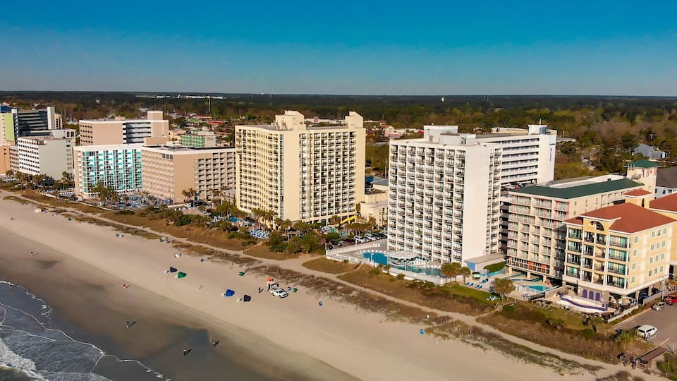 A coastal cityscape with high-rise hotels, a sandy beach, and a clear blue sky.