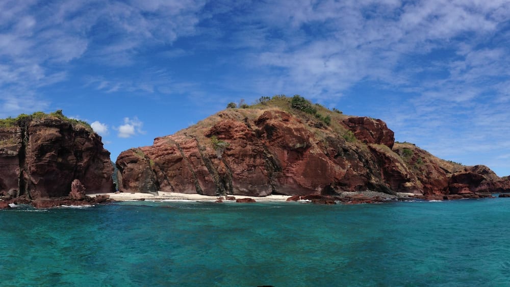 A rocky island with clear turquoise waters and a clear sky.