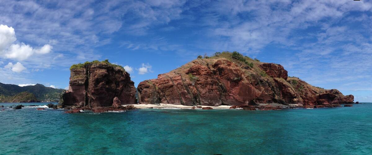 A rocky island with clear turquoise waters and a clear sky.