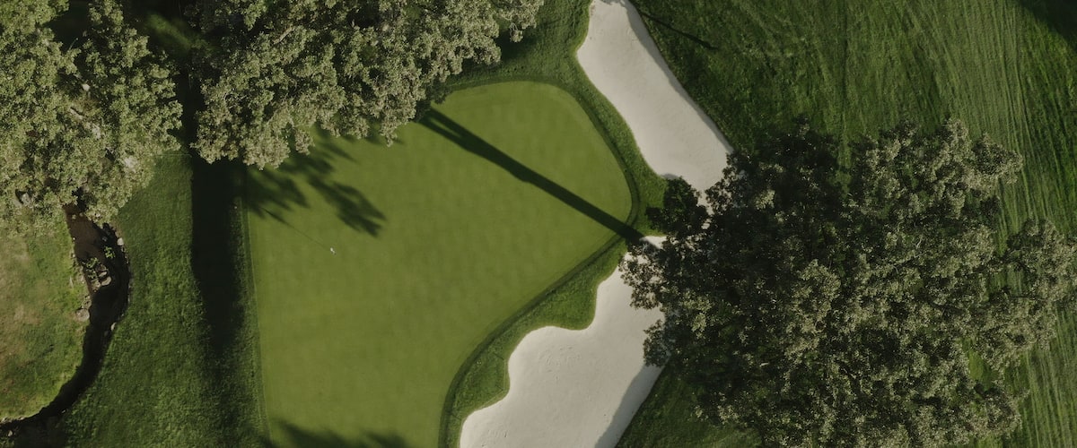 An aerial view of a golf course with sand bunkers and trees.
