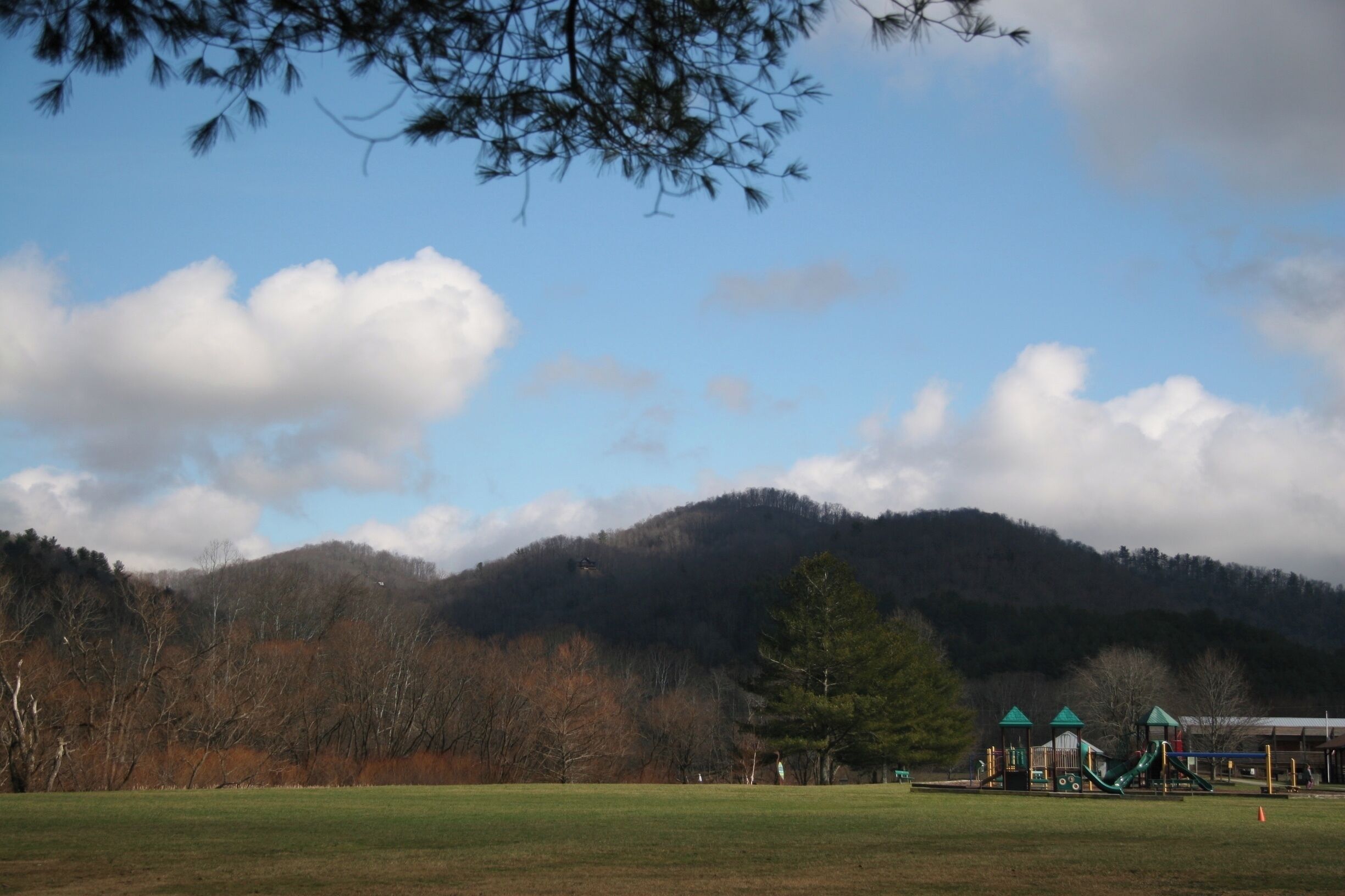 Nature was not designed by man but simply was created as is. However, eventually man came in to add developments, such as buildings or roads, or in this case a playground. One may think this is harmful to the untouched beauty that has always been there, but I see it more as an enhancement. It gives children and adults a place where he or she can enjoy each other’s company while simultaneously spend time in the outdoors, amongst the beauty.

I took this picture after carefully viewing the playground, the mountains, and the open field that lay around it. In this frame, viewers not only get a glimpse of the mountainous background and the playground in the distance, but a tree branch that is hovering at the top of the frame. I did this, so viewers may get the sense that he or she feel as if they are engulfed in the content of this image, not just looking at it on a screen.

#appalachianechoes