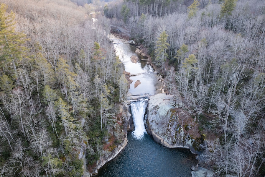 A river flowing through a forested valley with a waterfall.