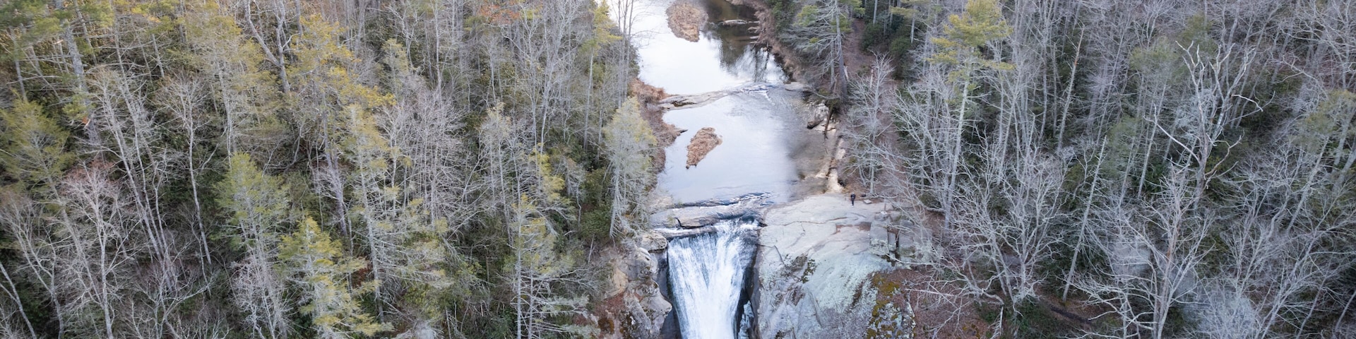 Un río serpentea por un valle arbolado con una cascada.