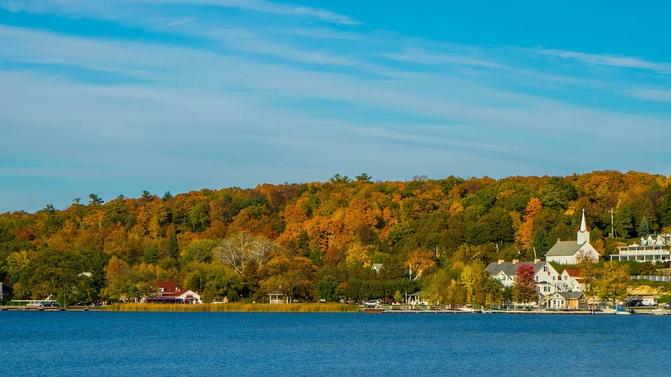 A lakeside town with autumn foliage, a church, and residential buildings.