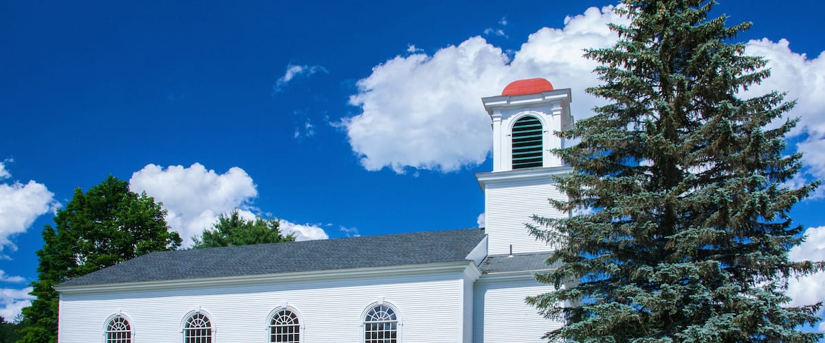 A white church with a red steeple and arched windows.