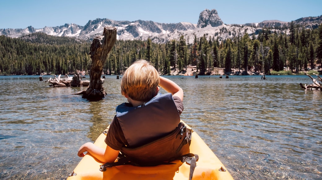 Una persona en un kayak sobre un lago tranquilo, con montañas al fondo.