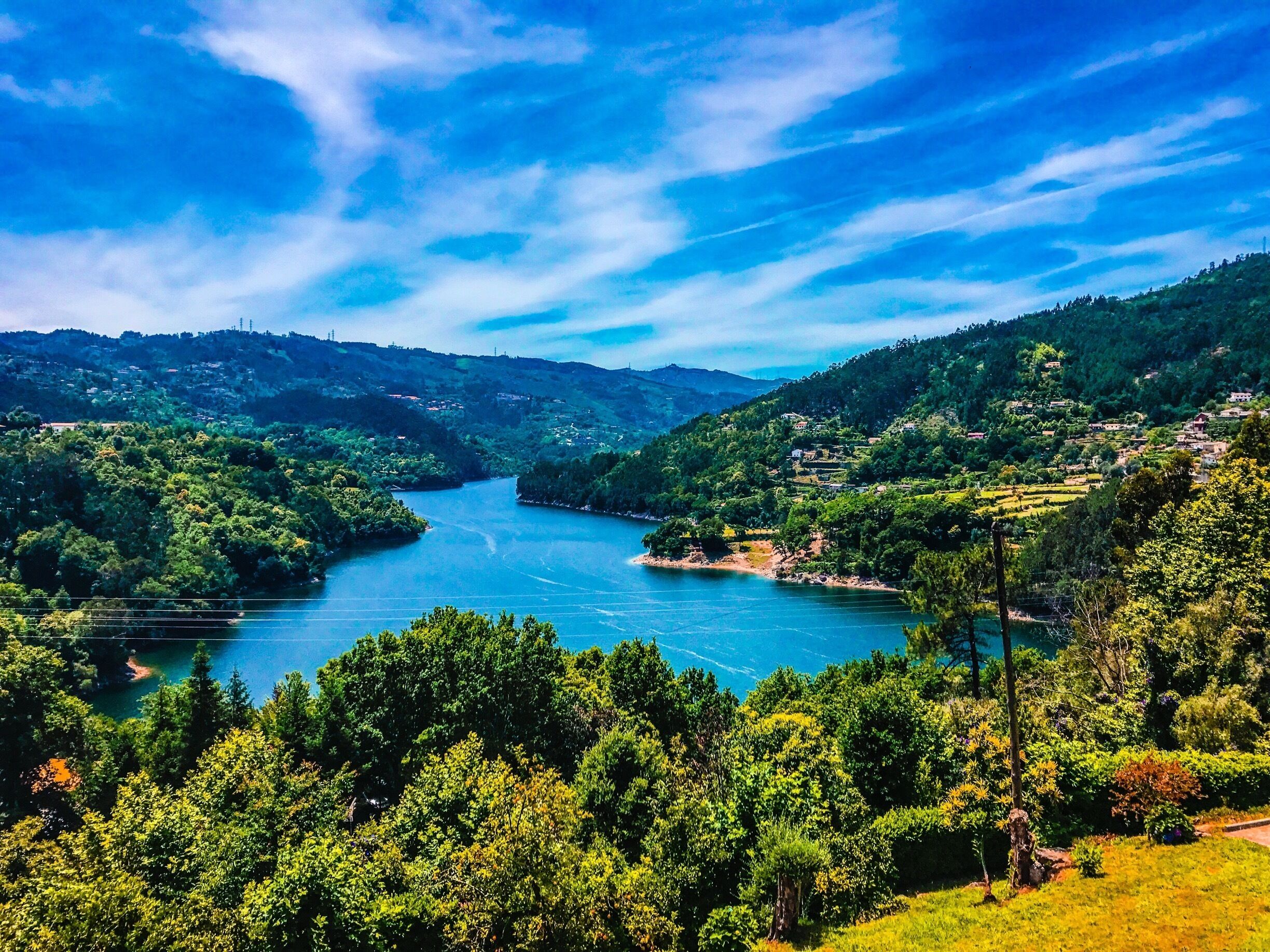 A river winding through a valley with dense green forests and hills in the background.