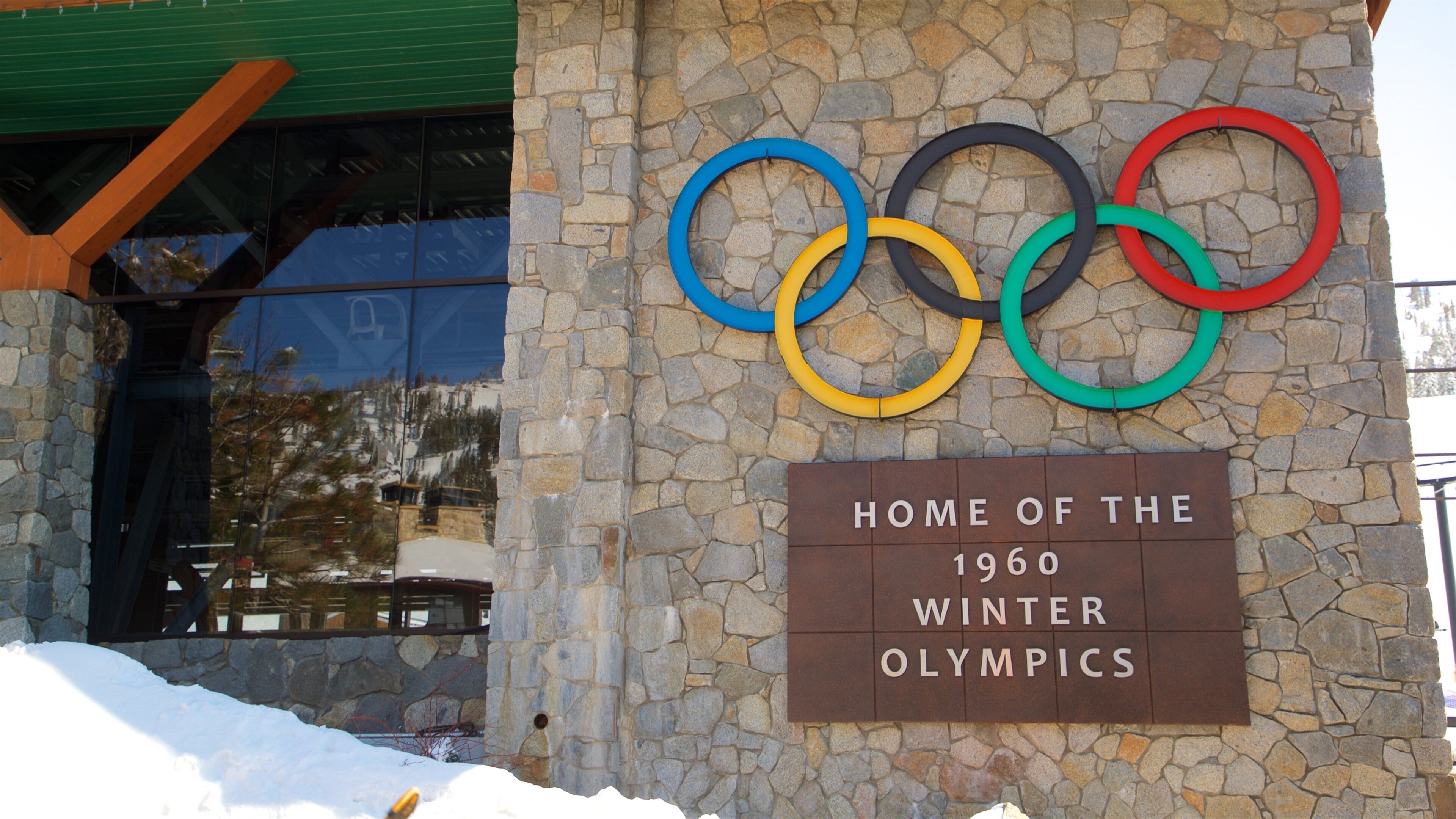 A stone wall with Olympic rings and a sign that reads "Home of the 1960 Winter Olympics".