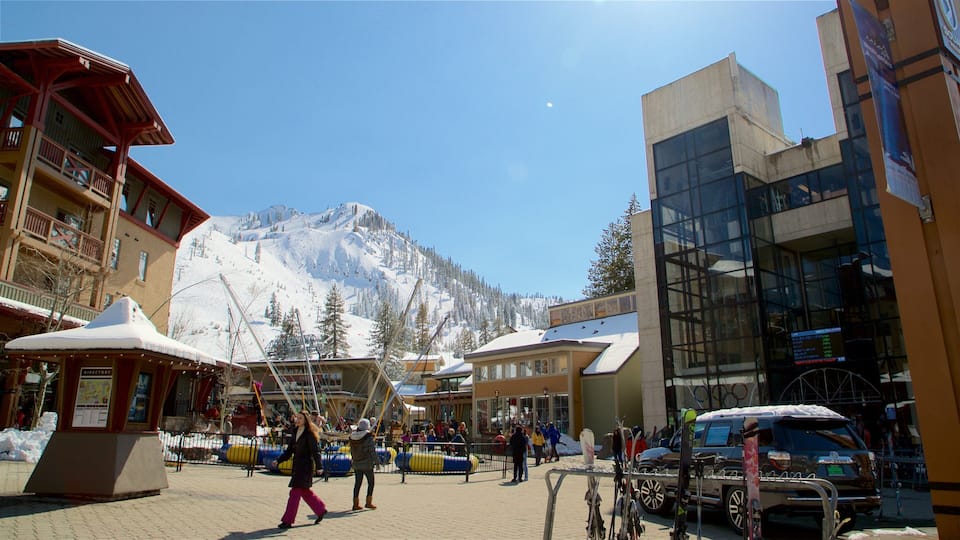 A snowy mountain town with a ski lift, buildings, and a clear blue sky.