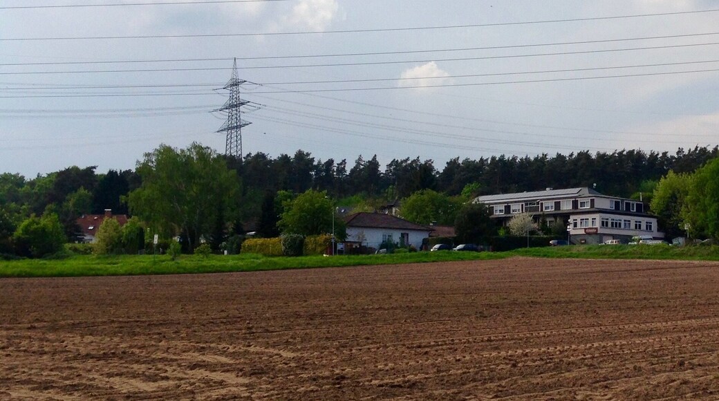 Der Stadtteil Bulau der Stadt Rödermark von einem parallel zu Dreieichbahn verlaufenden Fahrradweg aus fotografiert. Auf der rechten Bildseite ist das ansässige Hotel zu erkennen. Im oberen Bereich des Bildes sind Hochspannungsleitungen zum/vom Umspannwerk Urberach abgebildet.