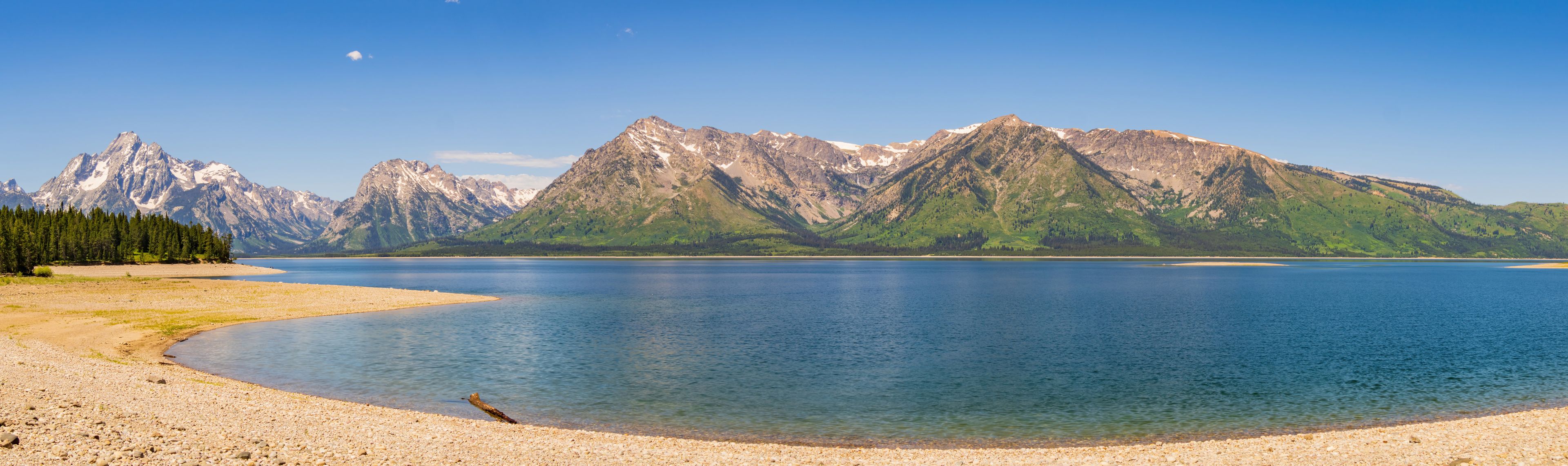 A calm lake surrounded by mountains with a clear sky.