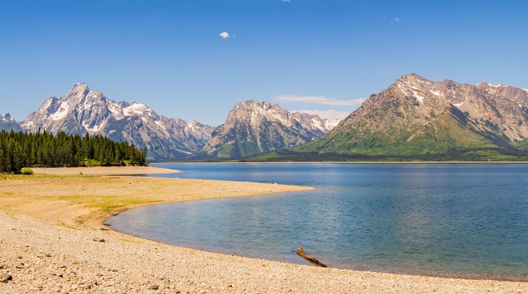 A calm lake surrounded by mountains with a clear sky.