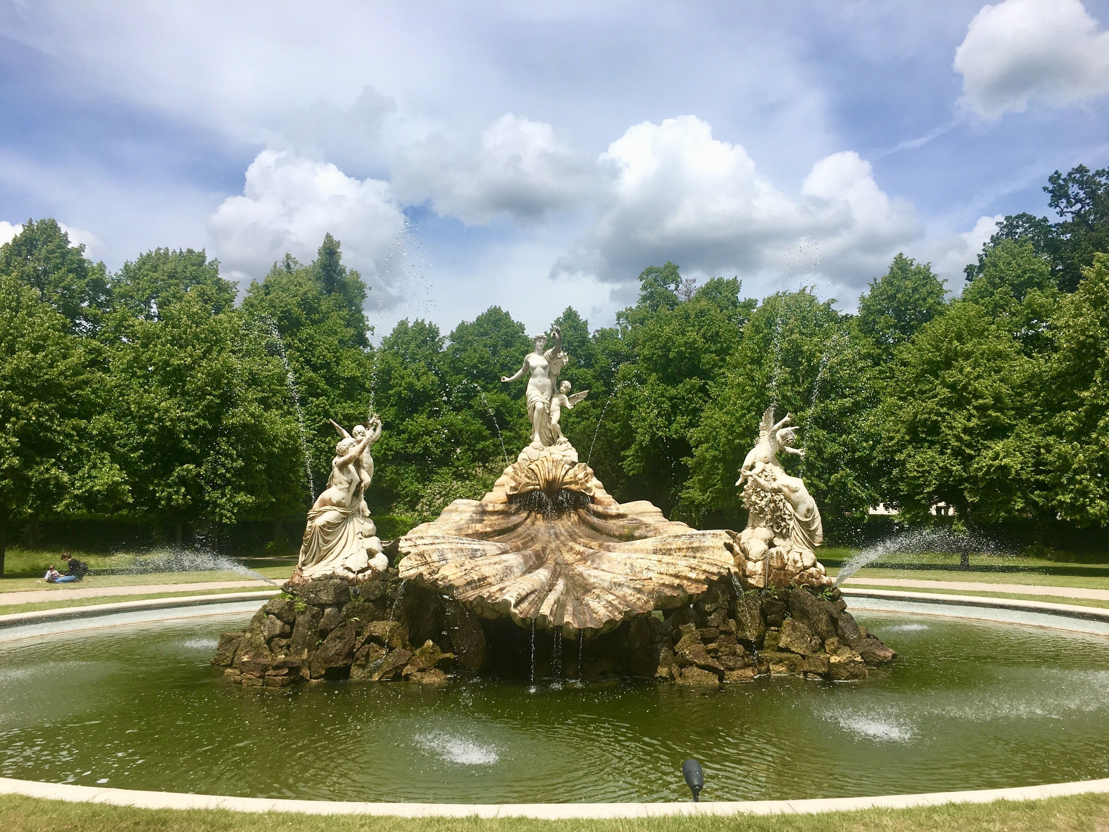 A fountain with three statues in a park.