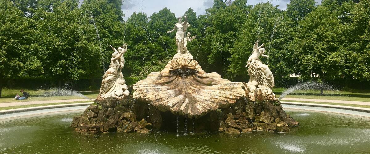 A fountain with three statues in a park.