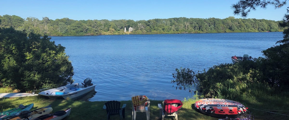 A lakeside view with kayaks, chairs, and a paddleboard.