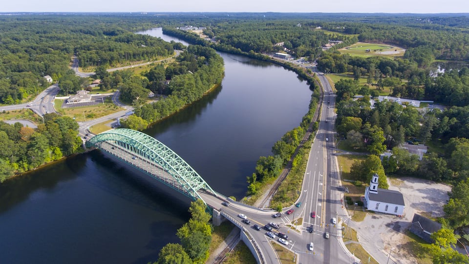 A river with a bridge, roads, and surrounding greenery.