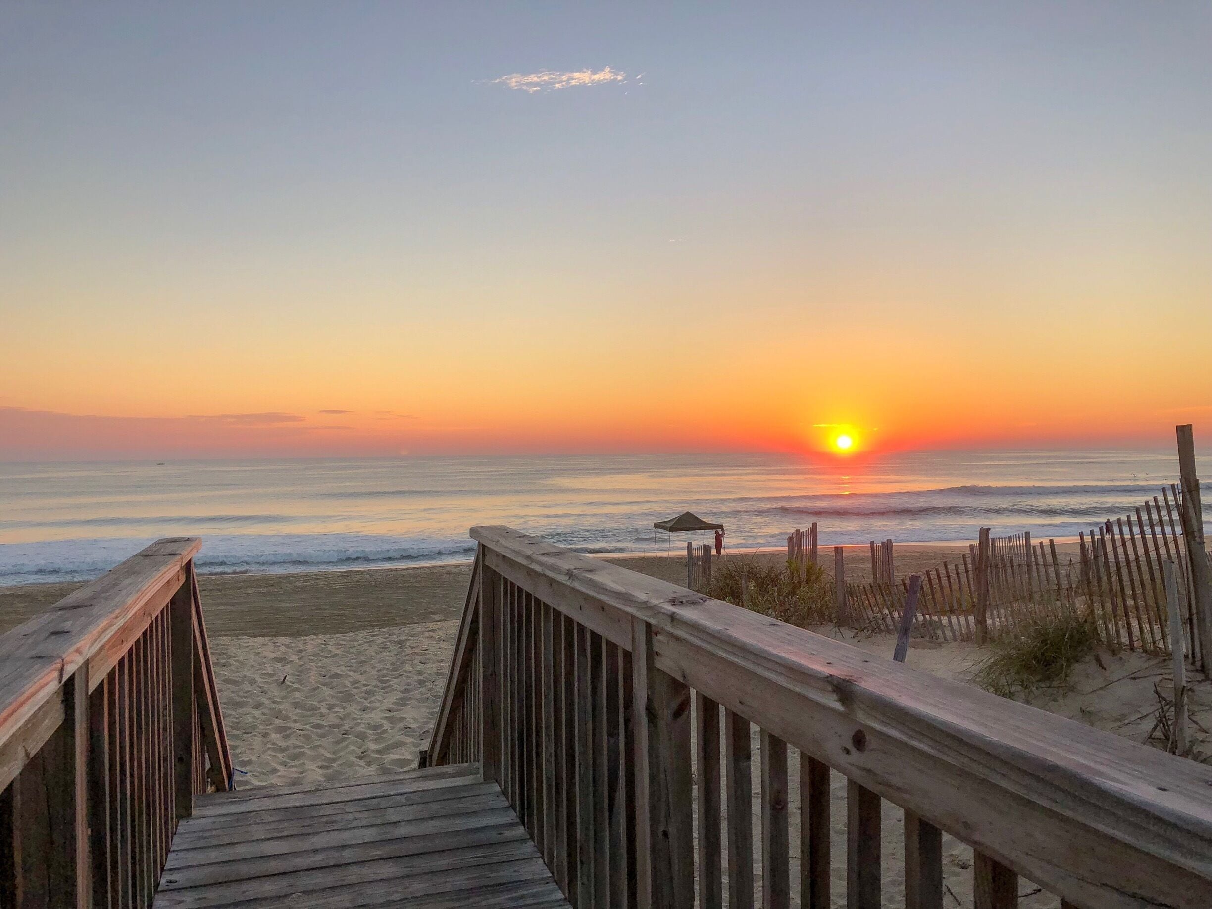 A wooden boardwalk leading to a beach at sunset.