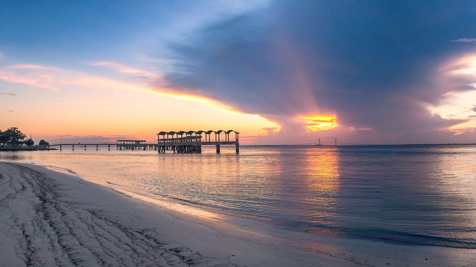 A beach with a pier and sunset.