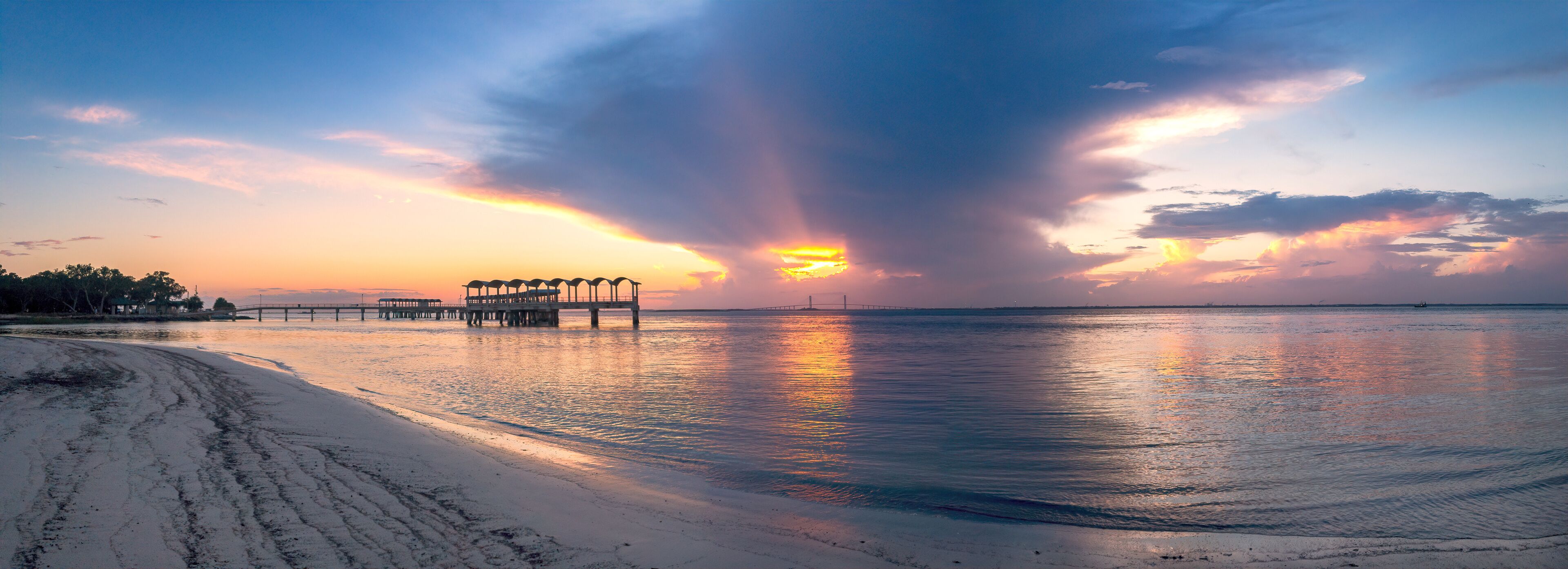 A beach with a pier and sunset.