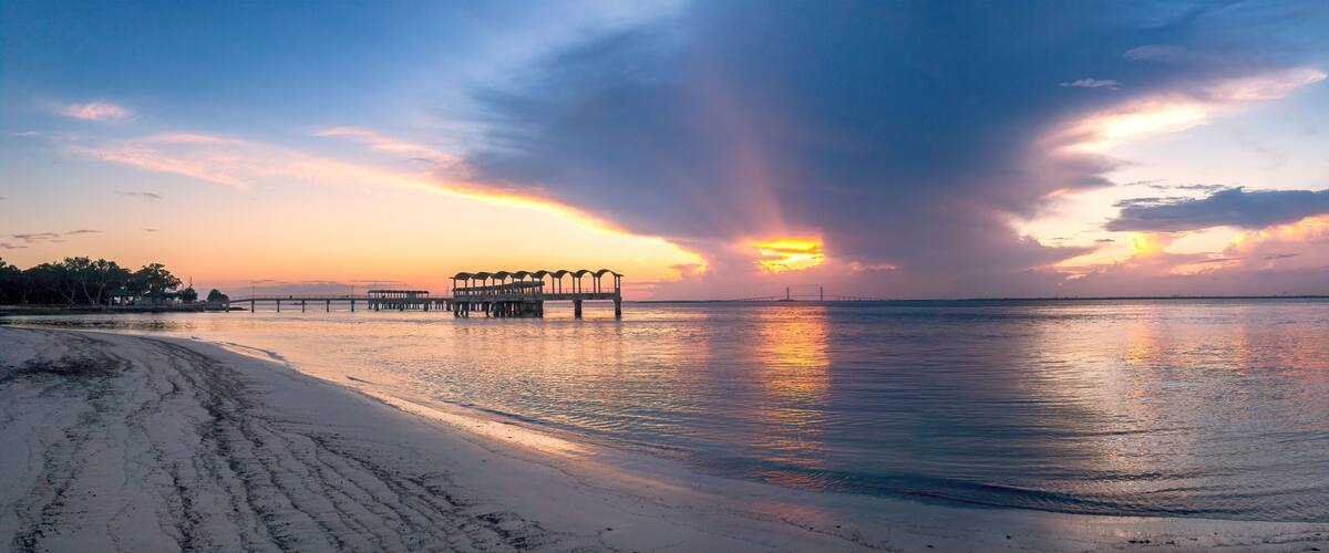 A beach with a pier and sunset.