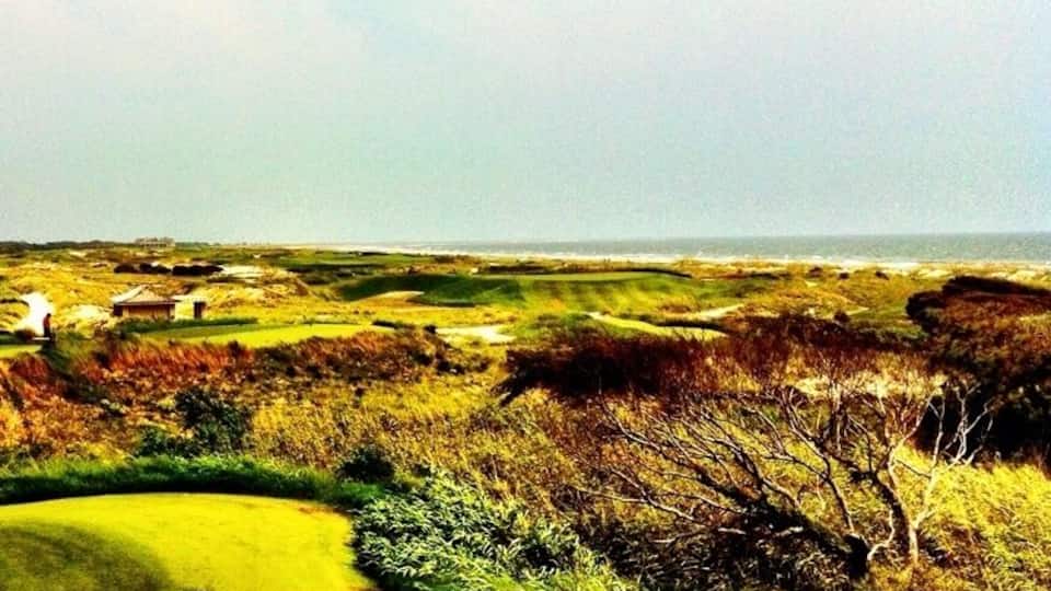 Ein Golfplatz mit einem Wasserhindernis, einem Bunker und weiter Aussicht auf den Ozean.