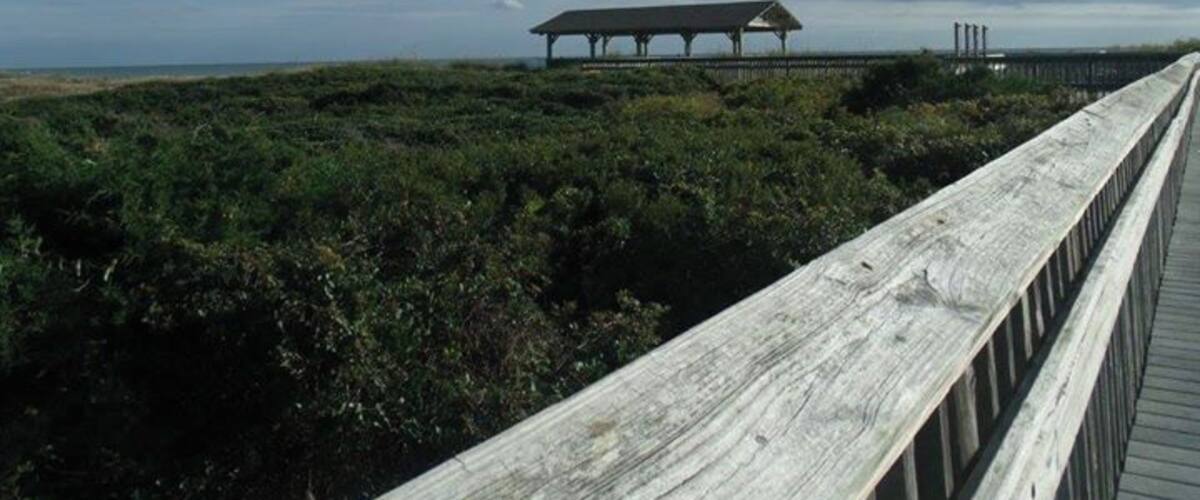 Board walk and beach pavilion over the sand dunes to the beach.