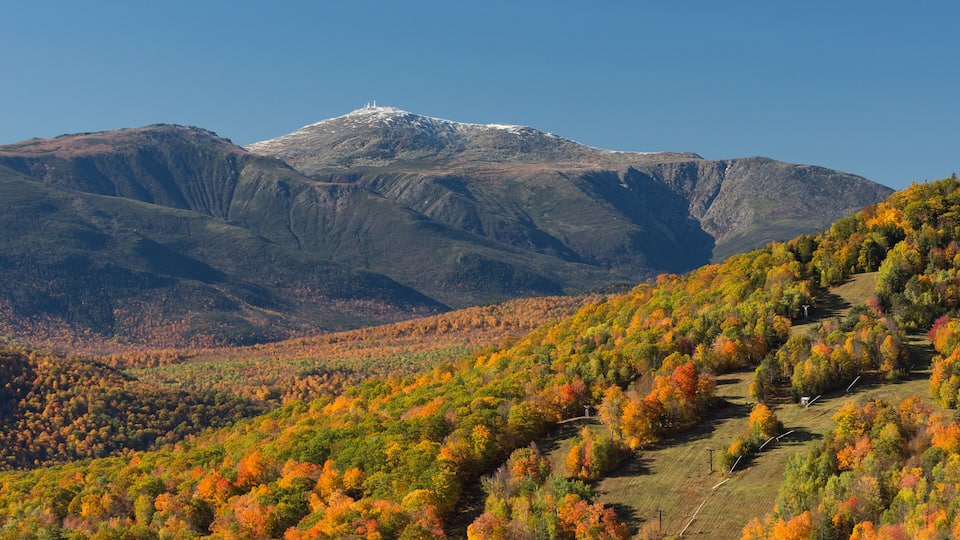 A mountainous landscape with autumn foliage and a snow-capped peak.