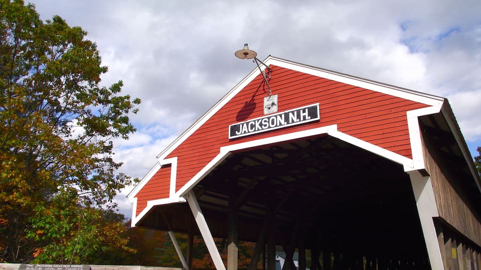 A covered bridge with a red roof and white trim, labeled "Jackson, N.H."