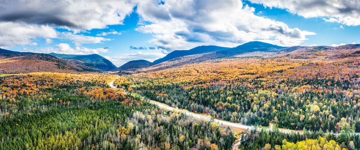 A mountainous landscape with autumn foliage, a winding road, and a valley.