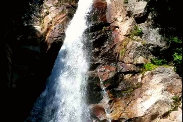 A waterfall cascading down a rocky cliff surrounded by greenery.