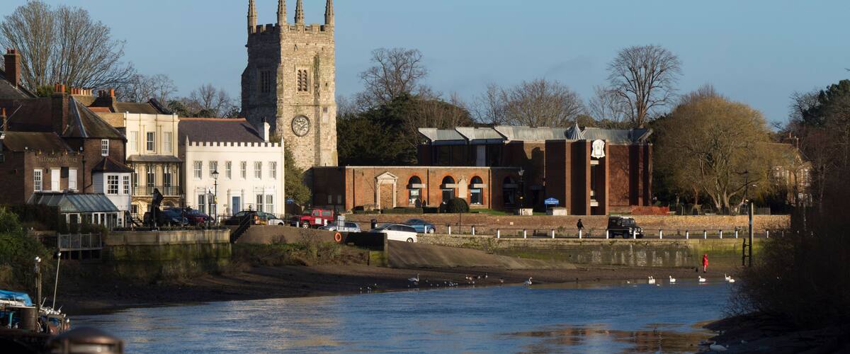 A river with boats, a tower, and buildings along the riverbank.