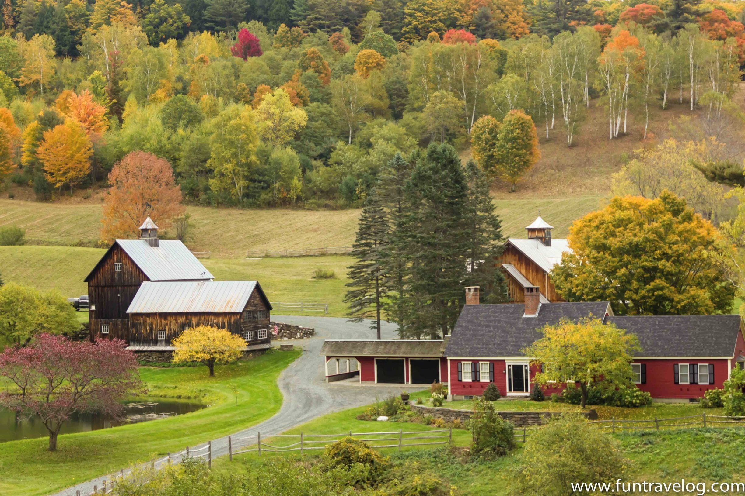 A rural landscape with barns, a red house, and autumn-colored trees.