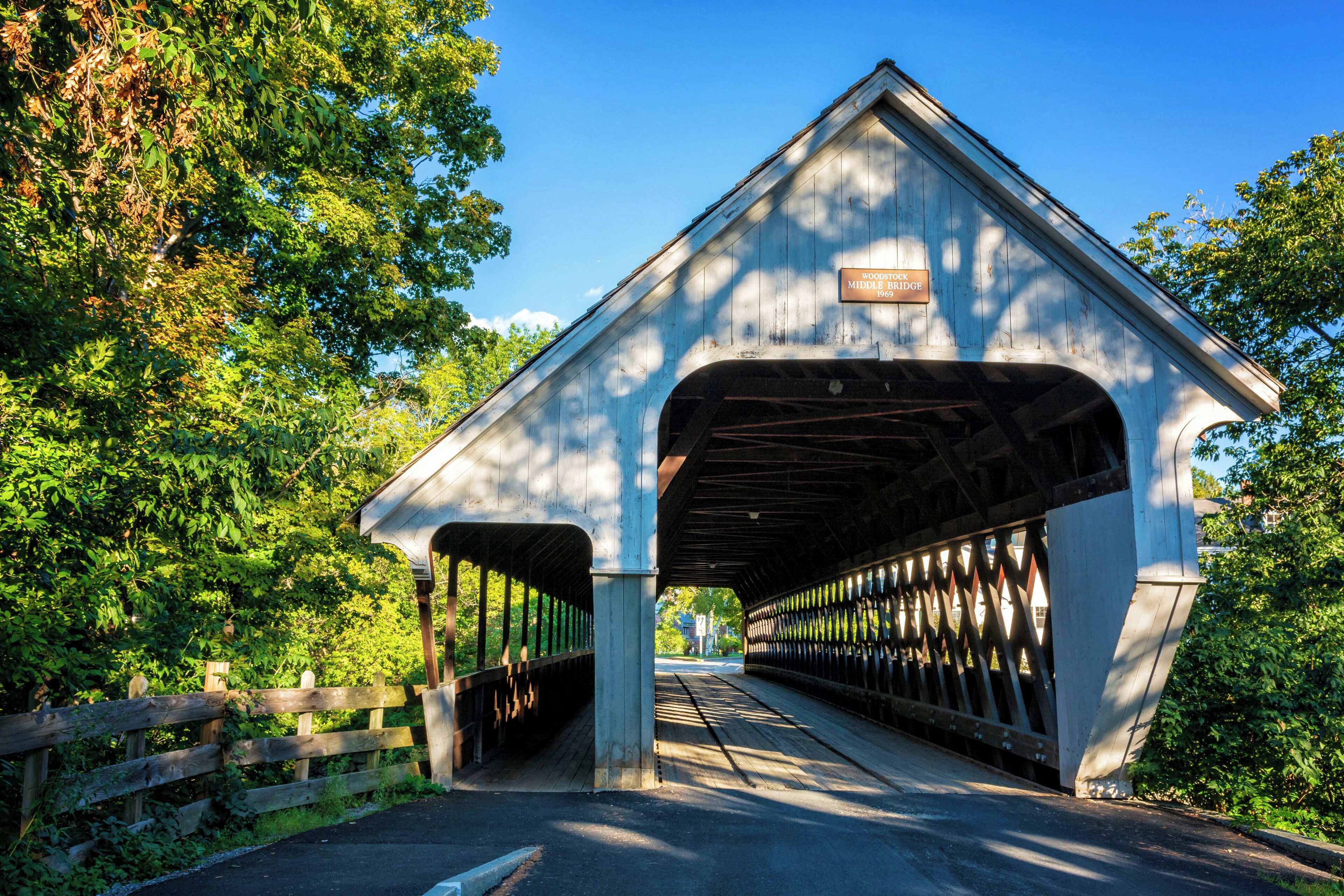 A covered wooden bridge with a sign reading "Woodstock Middle Bridge 1893."