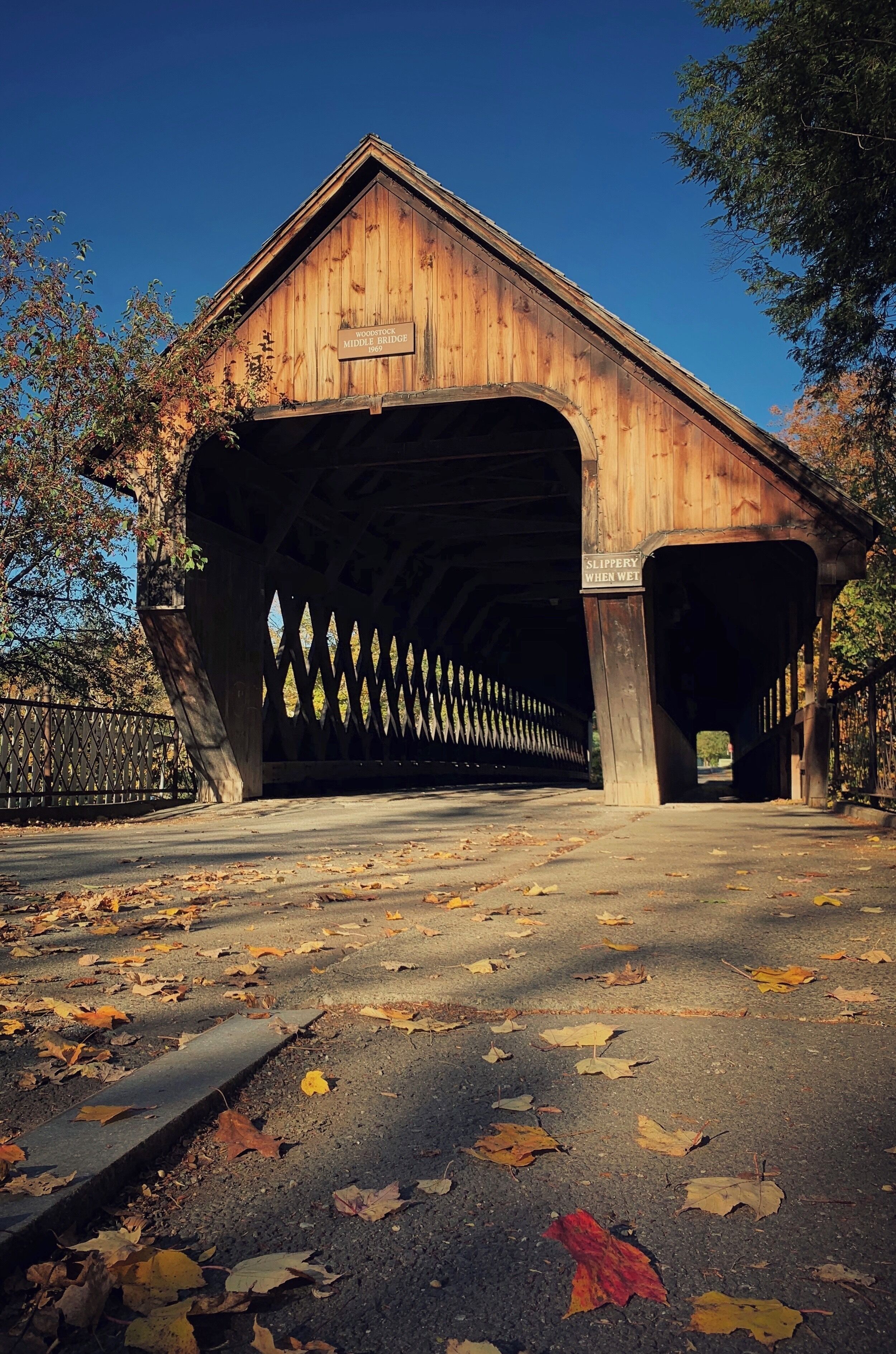 A wooden covered bridge with a sign reading "Woodford Middle Bridge."