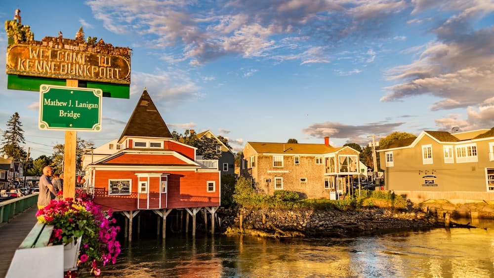 Eine Stadt am Wasser mit einem Schild, auf dem 'Willkommen in Kennebecport' und 'Mathew J. Lanigan Brücke' steht.