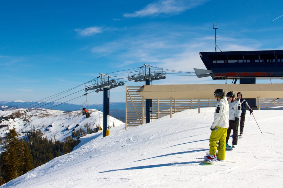 A ski lift, a wooden structure, and a snowy mountain landscape.